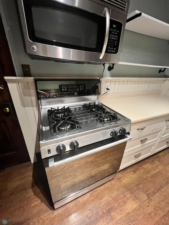 kitchen featuring hardwood / wood-style floors, stainless steel appliances, and white cabinetry