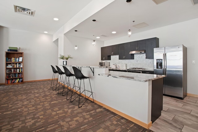 kitchen with dark hardwood / wood-style floors, a breakfast bar, stainless steel appliances, and decorative light fixtures