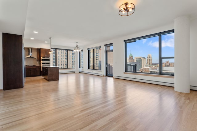 unfurnished living room featuring baseboard heating, light hardwood / wood-style flooring, and a notable chandelier