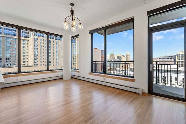 empty room with a notable chandelier, a baseboard radiator, and light hardwood / wood-style flooring