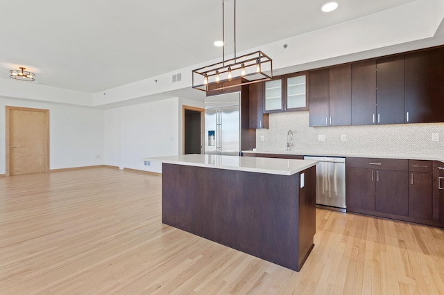 kitchen with decorative backsplash, stainless steel appliances, light hardwood / wood-style floors, a kitchen island, and hanging light fixtures