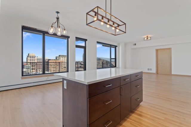 kitchen with dark brown cabinetry, a kitchen island, a healthy amount of sunlight, and light wood-type flooring