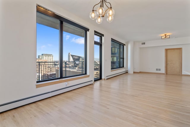 empty room with light wood-type flooring, a baseboard radiator, and an inviting chandelier