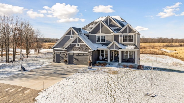 view of front facade featuring stone siding, covered porch, driveway, and an attached garage