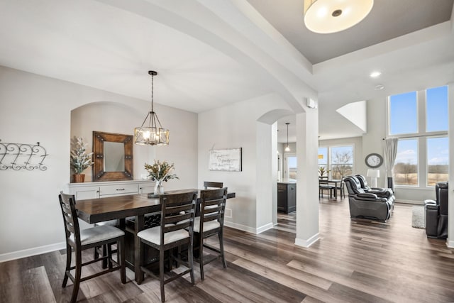 dining room featuring baseboards, arched walkways, and dark wood-style floors