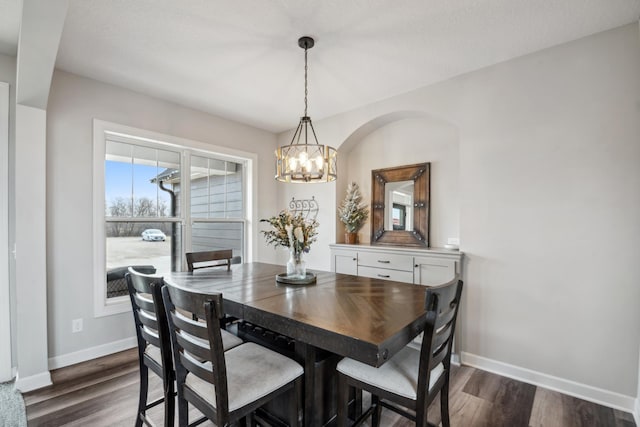 dining room featuring dark wood finished floors, a chandelier, and baseboards