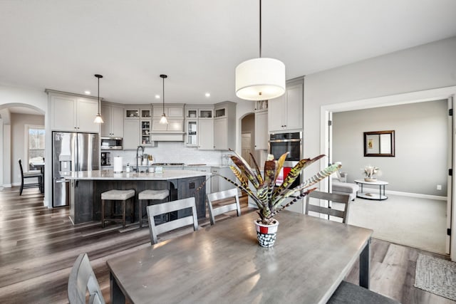 dining space featuring recessed lighting, dark wood-style floors, arched walkways, and baseboards