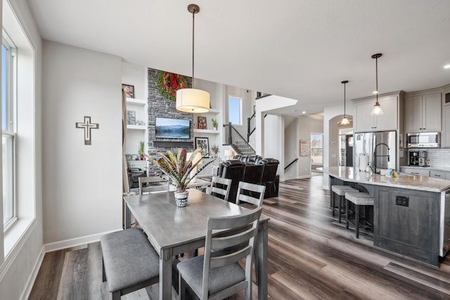 dining room with stairs, dark wood-type flooring, and baseboards