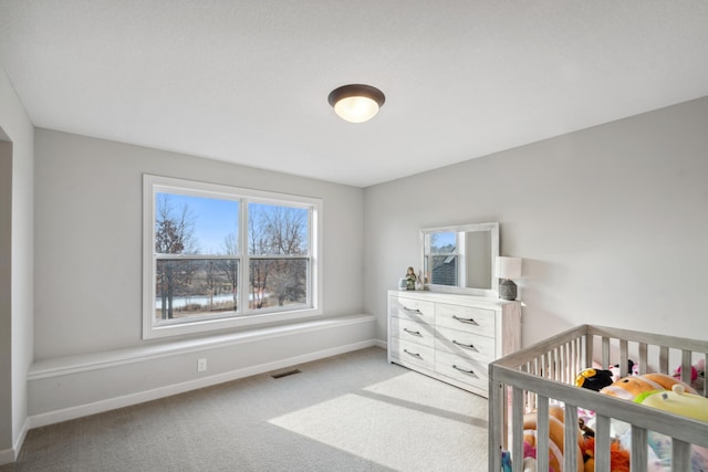 bedroom with a nursery area, visible vents, baseboards, and carpet