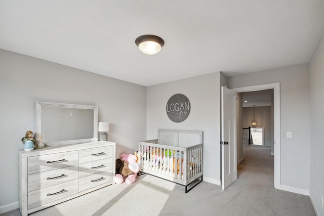 bedroom featuring a crib, carpet flooring, and baseboards