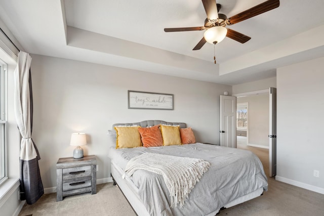 bedroom featuring a raised ceiling, baseboards, carpet floors, and ceiling fan