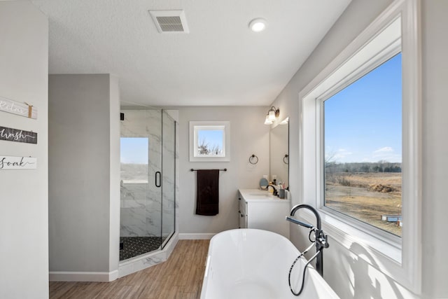 full bathroom with vanity, wood finished floors, visible vents, a marble finish shower, and a soaking tub