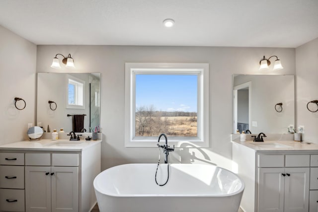 full bath with a freestanding tub, two vanities, and a sink