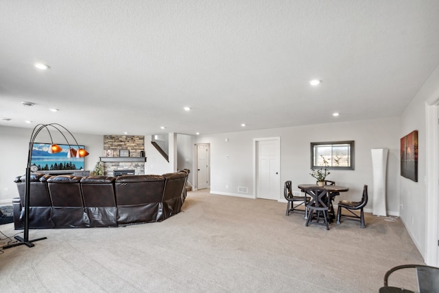 living room featuring baseboards, light colored carpet, recessed lighting, a fireplace, and a textured ceiling