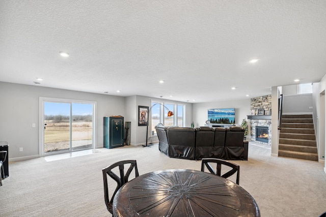 dining area featuring light carpet, recessed lighting, a fireplace, and a textured ceiling