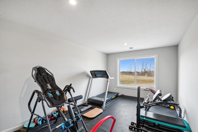 workout room with a textured ceiling and baseboards