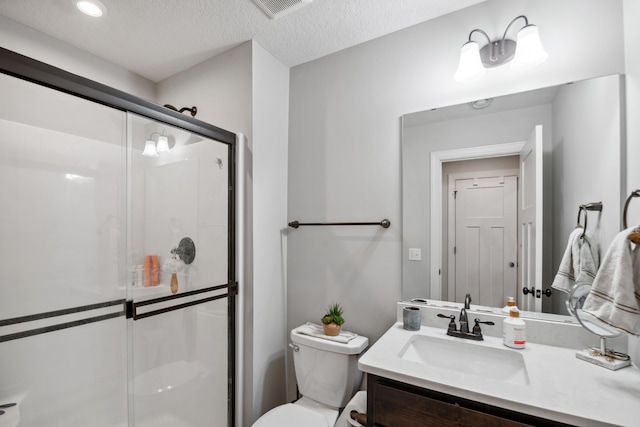 bathroom featuring vanity, visible vents, a shower stall, a textured ceiling, and toilet