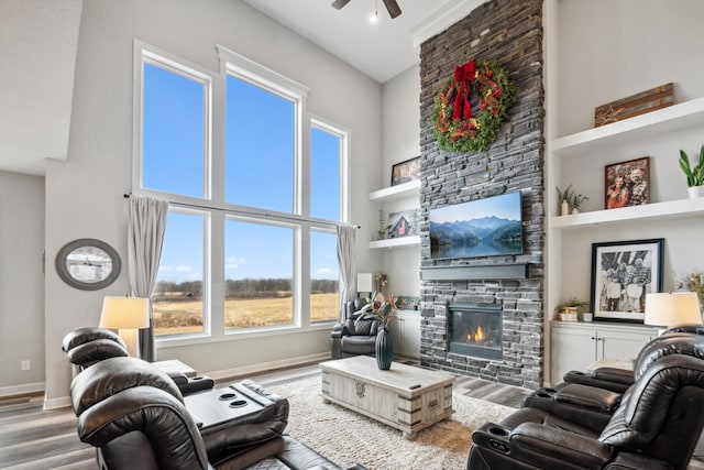 18340 Forest Rd N, Forest Lake, MN 55025 - living room with a stone fireplace, wood finished floors, a ceiling fan, a high ceiling, and plenty of natural light