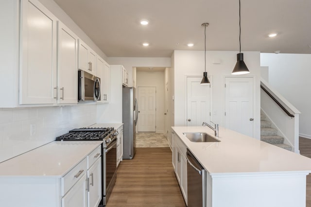 kitchen featuring pendant lighting, sink, appliances with stainless steel finishes, a kitchen island with sink, and white cabinets