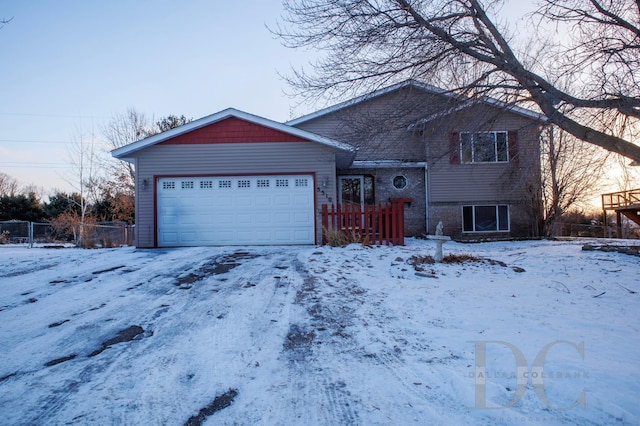 tri-level home with brick siding, an attached garage, and fence