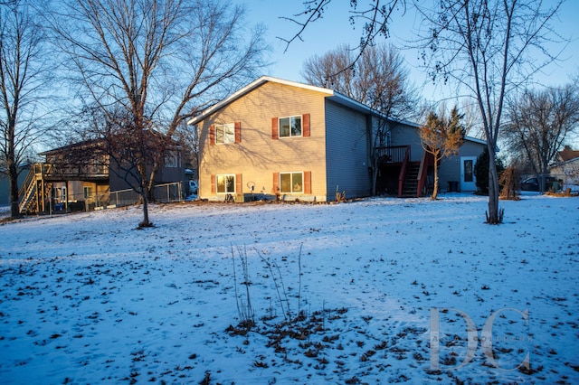 snow covered house with fence and stairway