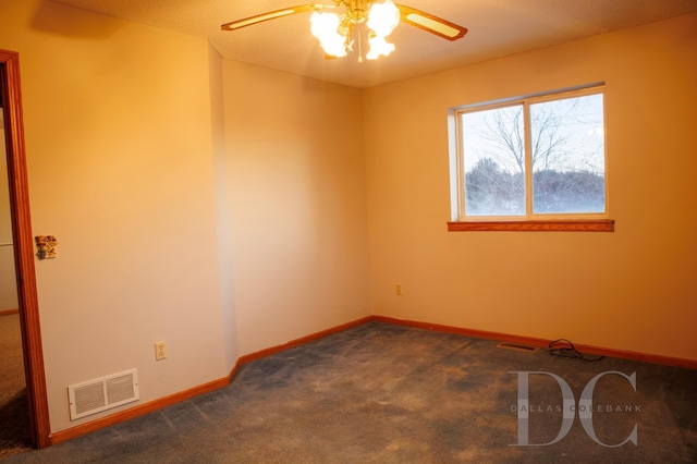 spare room with ceiling fan, dark carpet, visible vents, and baseboards