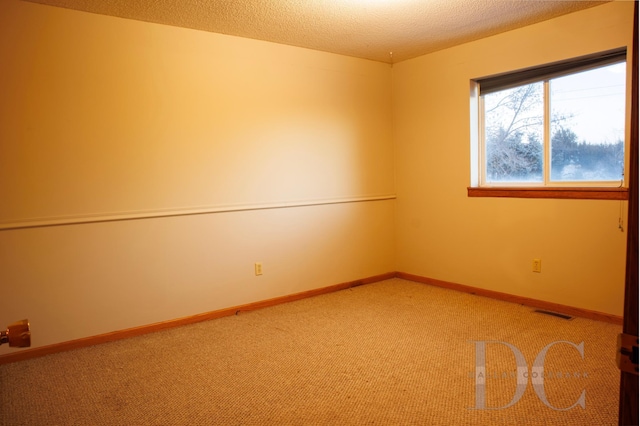 unfurnished room with a textured ceiling, visible vents, light colored carpet, and baseboards