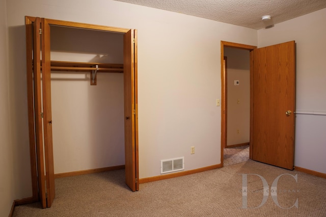 unfurnished bedroom featuring baseboards, visible vents, carpet, a textured ceiling, and a closet