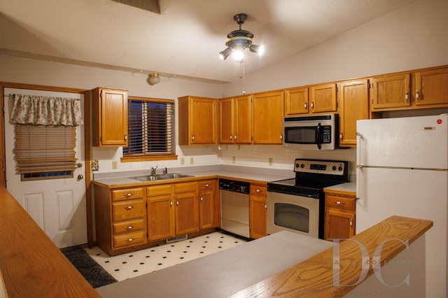 kitchen with appliances with stainless steel finishes, lofted ceiling, light countertops, and a sink