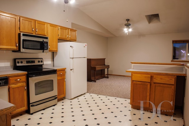 kitchen featuring lofted ceiling, light countertops, appliances with stainless steel finishes, backsplash, and brown cabinetry