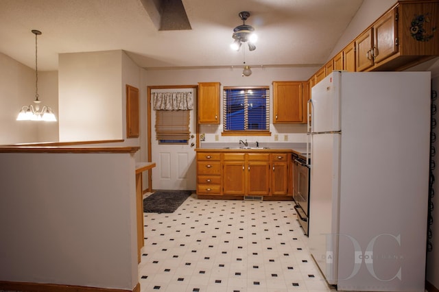 kitchen featuring a sink, brown cabinets, freestanding refrigerator, stainless steel electric stove, and decorative light fixtures