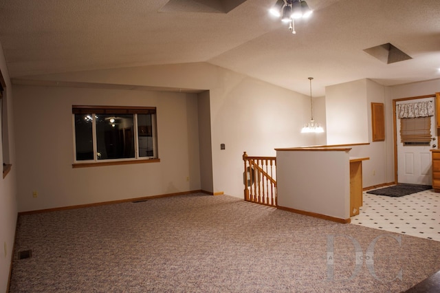 carpeted spare room with vaulted ceiling, a textured ceiling, visible vents, and baseboards