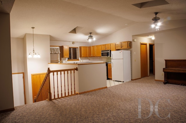 kitchen featuring decorative light fixtures, stainless steel microwave, freestanding refrigerator, vaulted ceiling, and a peninsula