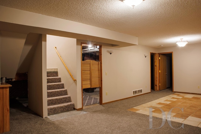 finished basement featuring baseboards, visible vents, stairway, carpet, and a textured ceiling