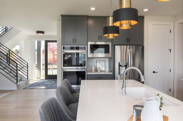 kitchen featuring stainless steel appliances, gray cabinets, light hardwood / wood-style floors, and sink