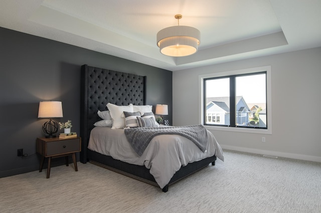 carpeted bedroom with a tray ceiling