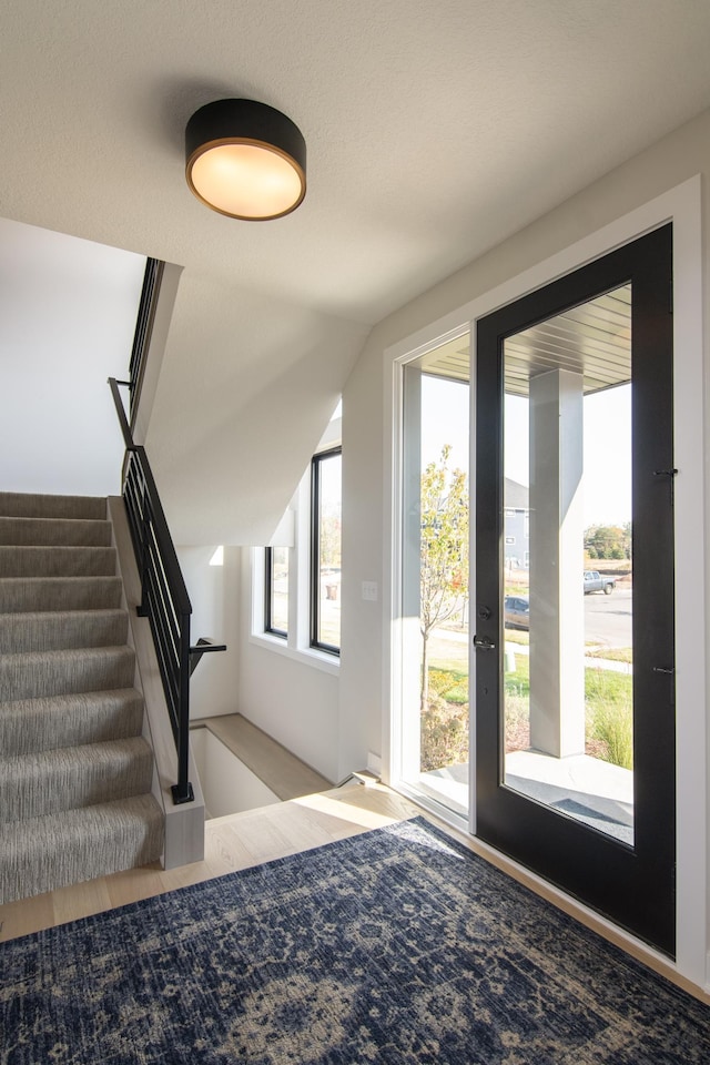 doorway with light hardwood / wood-style floors and a textured ceiling