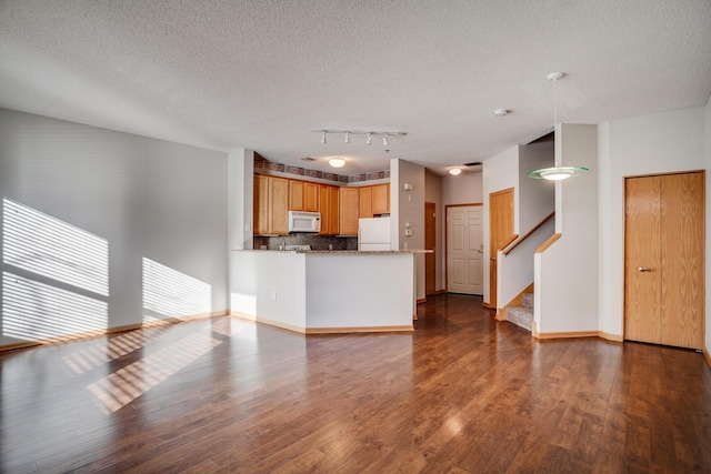 unfurnished living room with a textured ceiling, dark hardwood / wood-style flooring, and rail lighting