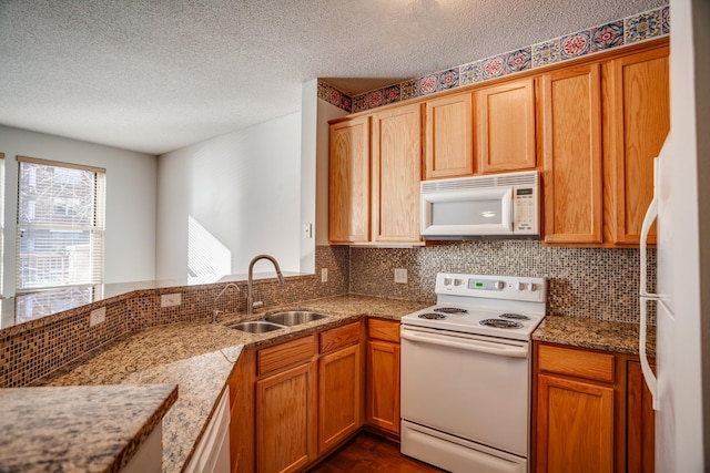 kitchen with a textured ceiling, decorative backsplash, white appliances, and sink