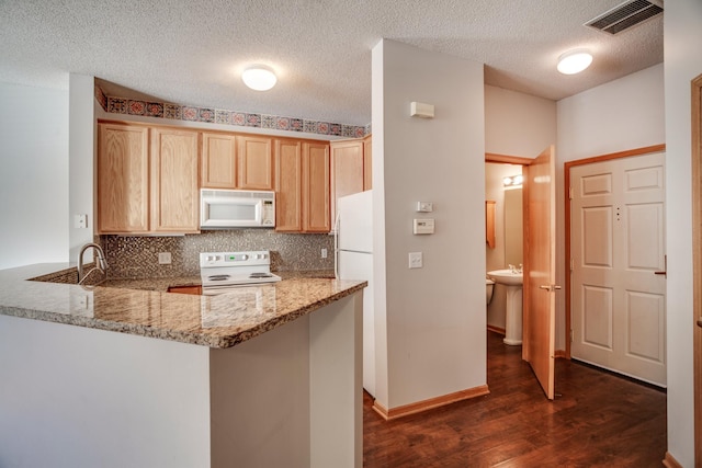 kitchen with kitchen peninsula, light stone countertops, dark hardwood / wood-style flooring, white appliances, and light brown cabinets