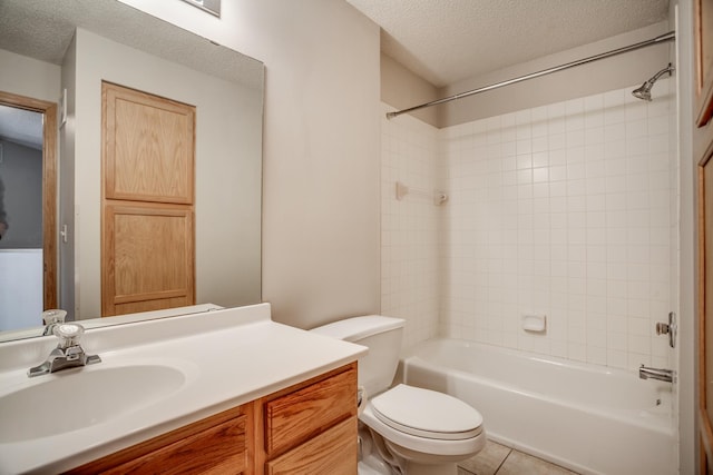 full bathroom featuring vanity, tile patterned floors, tiled shower / bath combo, toilet, and a textured ceiling