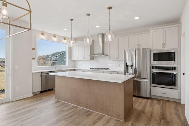 11459 Blazingstar Ln, Lake Elmo, MN 55042 - kitchen featuring appliances with stainless steel finishes, wall chimney exhaust hood, a kitchen island, light countertops, and light wood finished floors