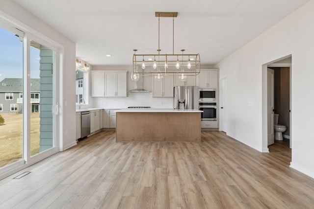 11459 Blazingstar Ln, Lake Elmo, MN 55042 - kitchen with appliances with stainless steel finishes, light wood-type flooring, tasteful backsplash, light countertops, and a kitchen island