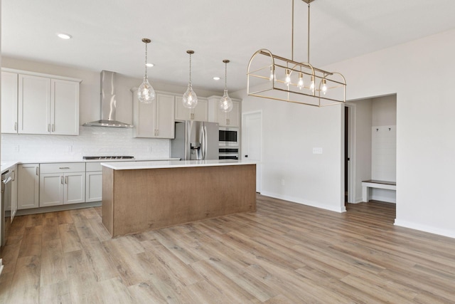 11459 Blazingstar Ln, Lake Elmo, MN 55042 - kitchen featuring appliances with stainless steel finishes, wall chimney range hood, a center island, tasteful backsplash, and light wood-style flooring