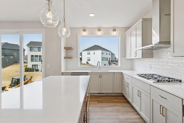 11459 Blazingstar Ln, Lake Elmo, MN 55042 - kitchen featuring a sink, wall chimney exhaust hood, light countertops, light wood-type flooring, and backsplash