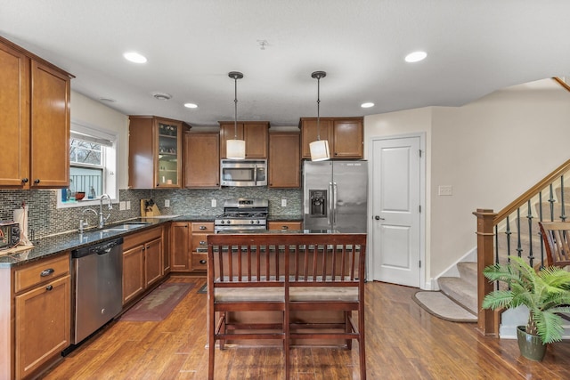 kitchen with sink, stainless steel appliances, dark wood-type flooring, tasteful backsplash, and pendant lighting