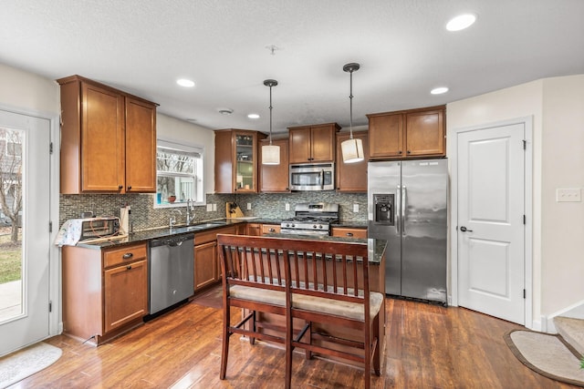 kitchen with decorative light fixtures, dark hardwood / wood-style flooring, stainless steel appliances, and sink