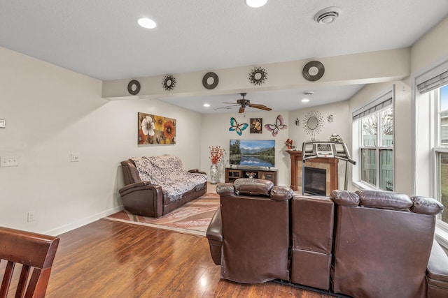 living room featuring wood-type flooring, a textured ceiling, and ceiling fan