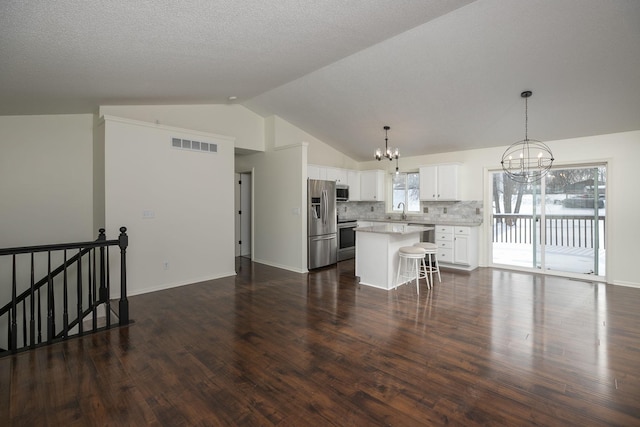 kitchen featuring appliances with stainless steel finishes, vaulted ceiling, a kitchen island, dark hardwood / wood-style floors, and white cabinetry