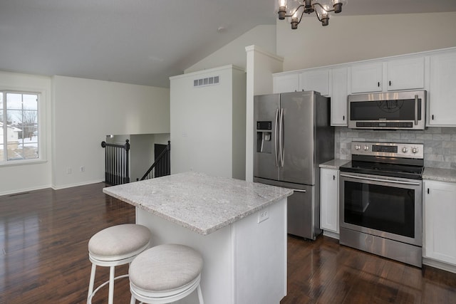 kitchen with white cabinetry, a kitchen island, vaulted ceiling, and appliances with stainless steel finishes